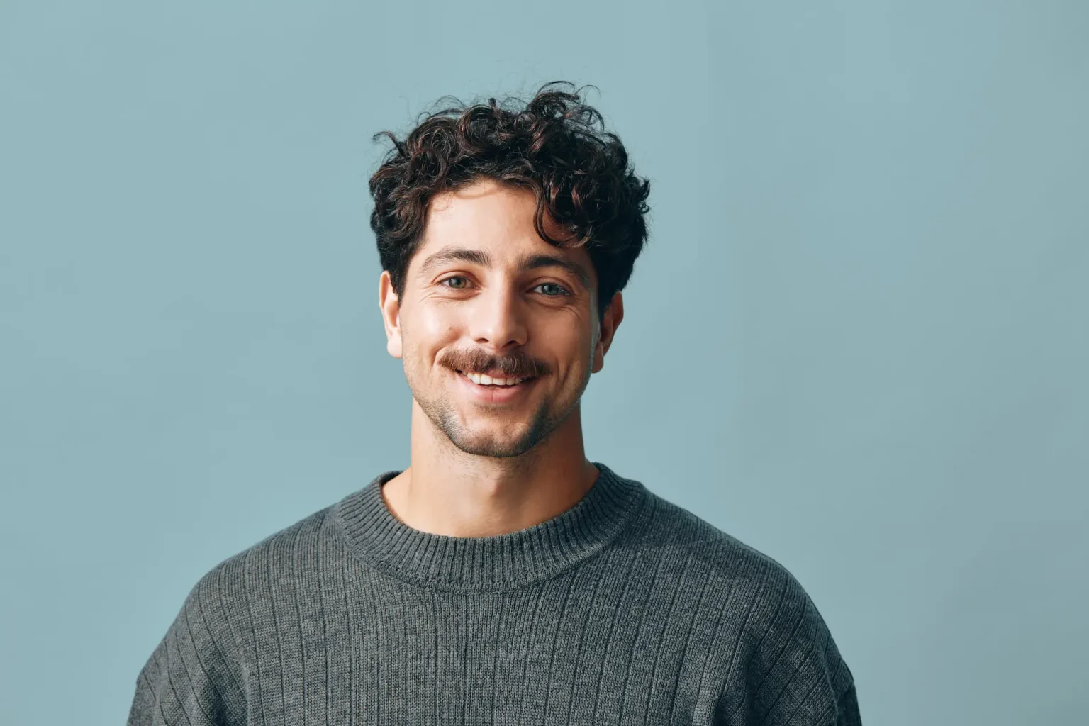 Smiling man in gray sweater studio portrait
